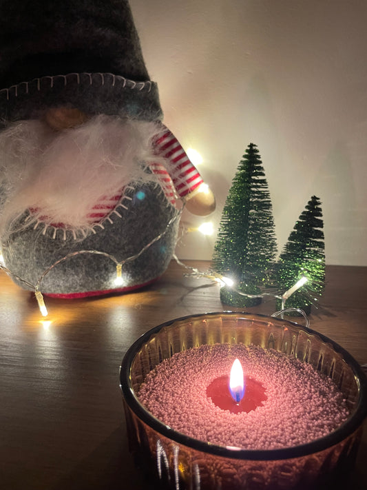 Een stijlvolle opstelling van Label Y Kaarsenzand in een XL glas, omringd door kerstdecoraties, met een warme en uitnodigende sfeer.