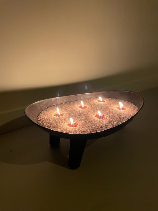 Label Y Aroma Candle Sand in een stijlvolle schaal met een brandende lont, omgeven door decoratieve elementen. Het geurzand verspreidt een subtiele geur en creëert een warme, uitnodigende sfeer in huis.